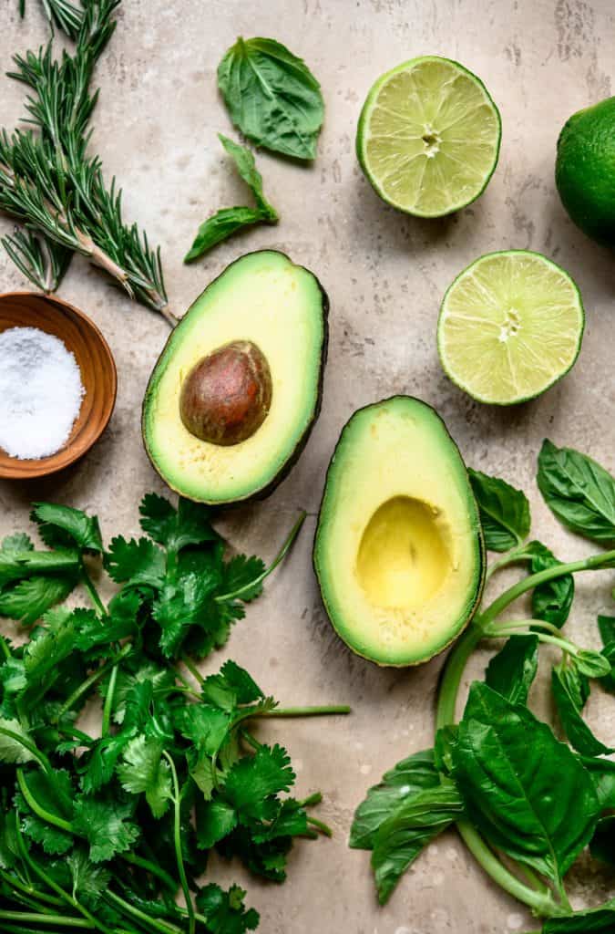 Overhead of ripe avocado, fresh herbs and sea salt