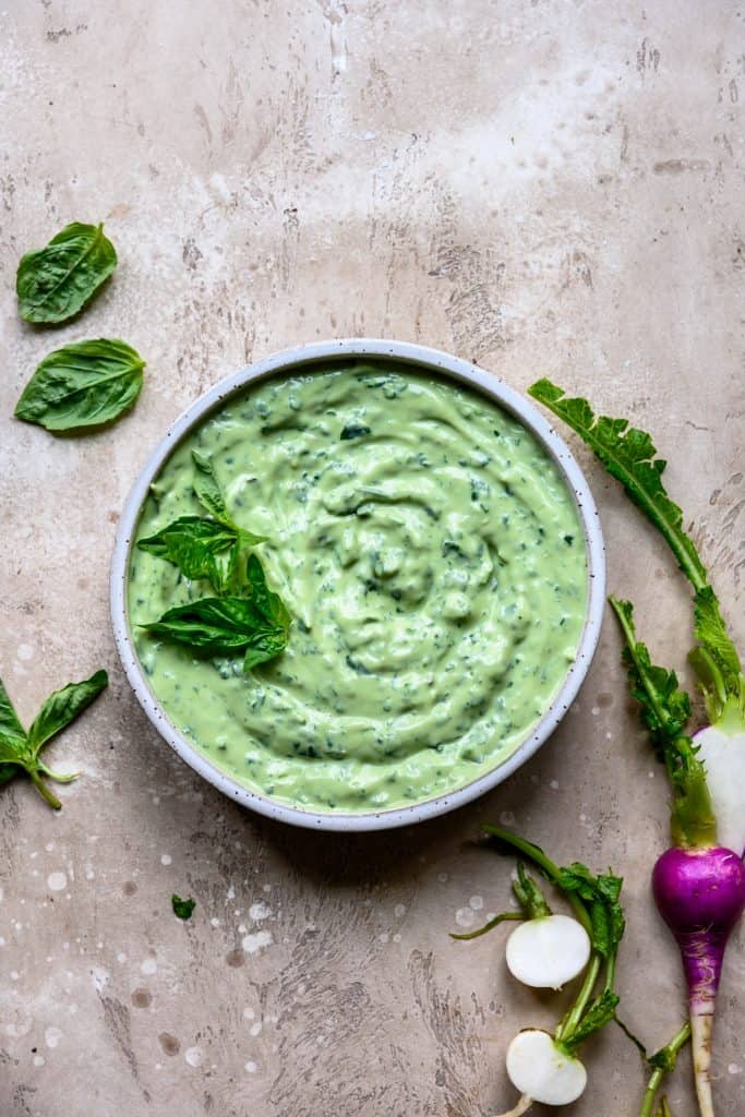 Overhead of herby whipped tofu dip in white bowl with radishes
