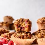 Side view of stacked vegan raspberry rhubarb muffins on pink background