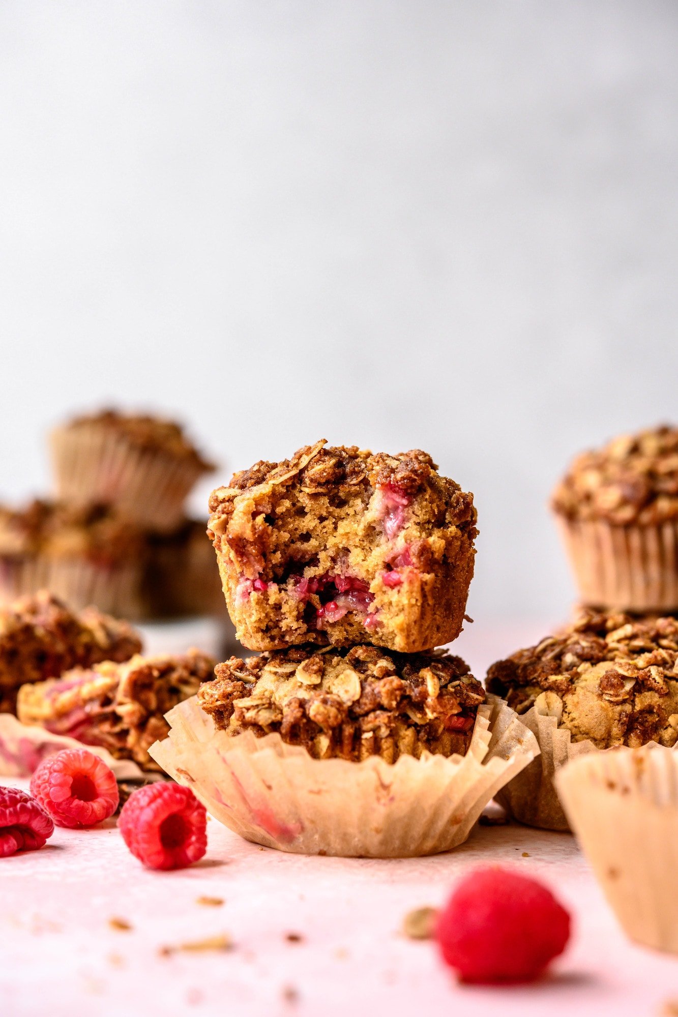 Side view of stacked vegan raspberry rhubarb muffins on pink background
