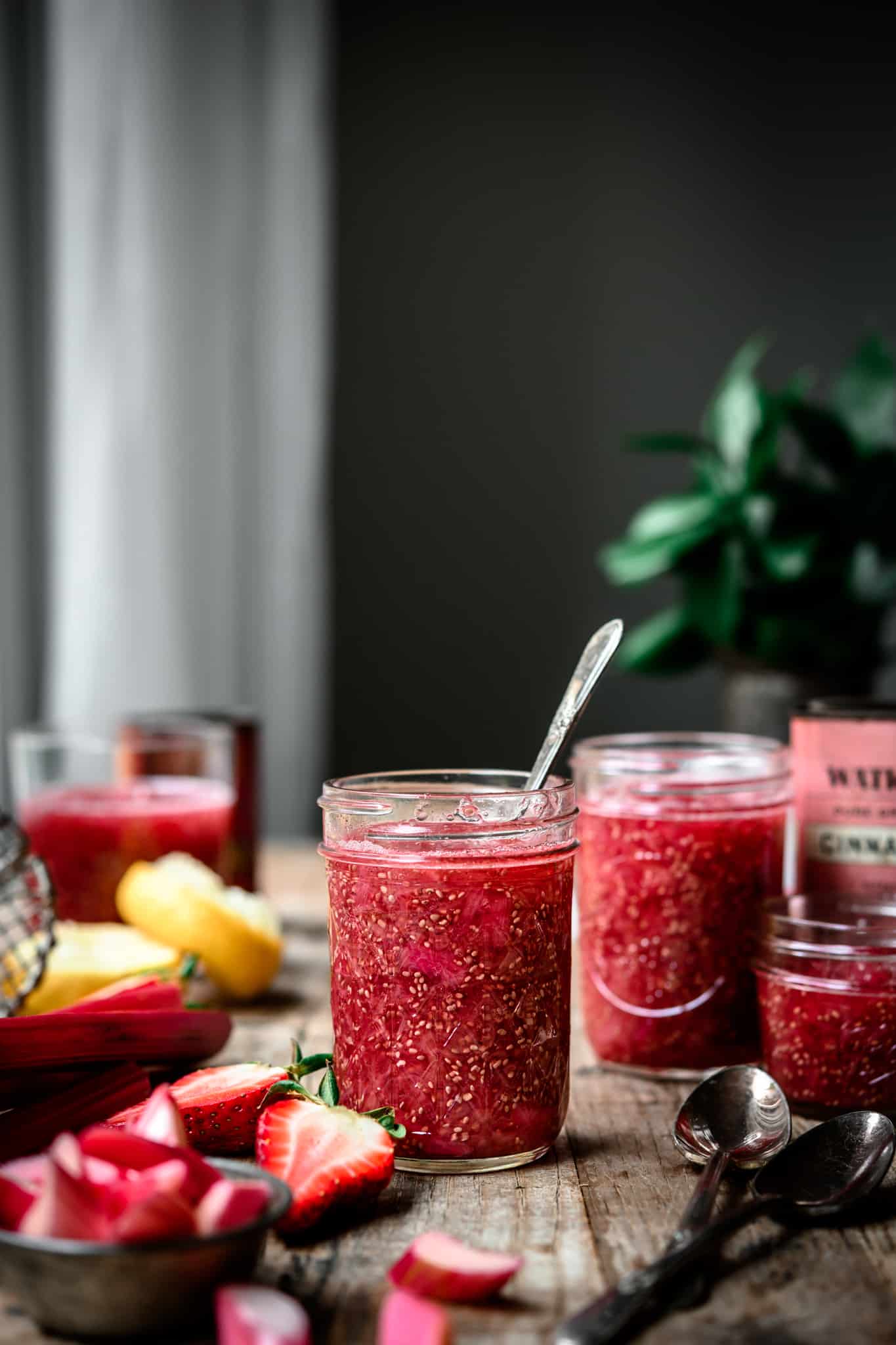 Side view of jar of rhubarb vanilla chia compote on a wood table, dark and moody photo
