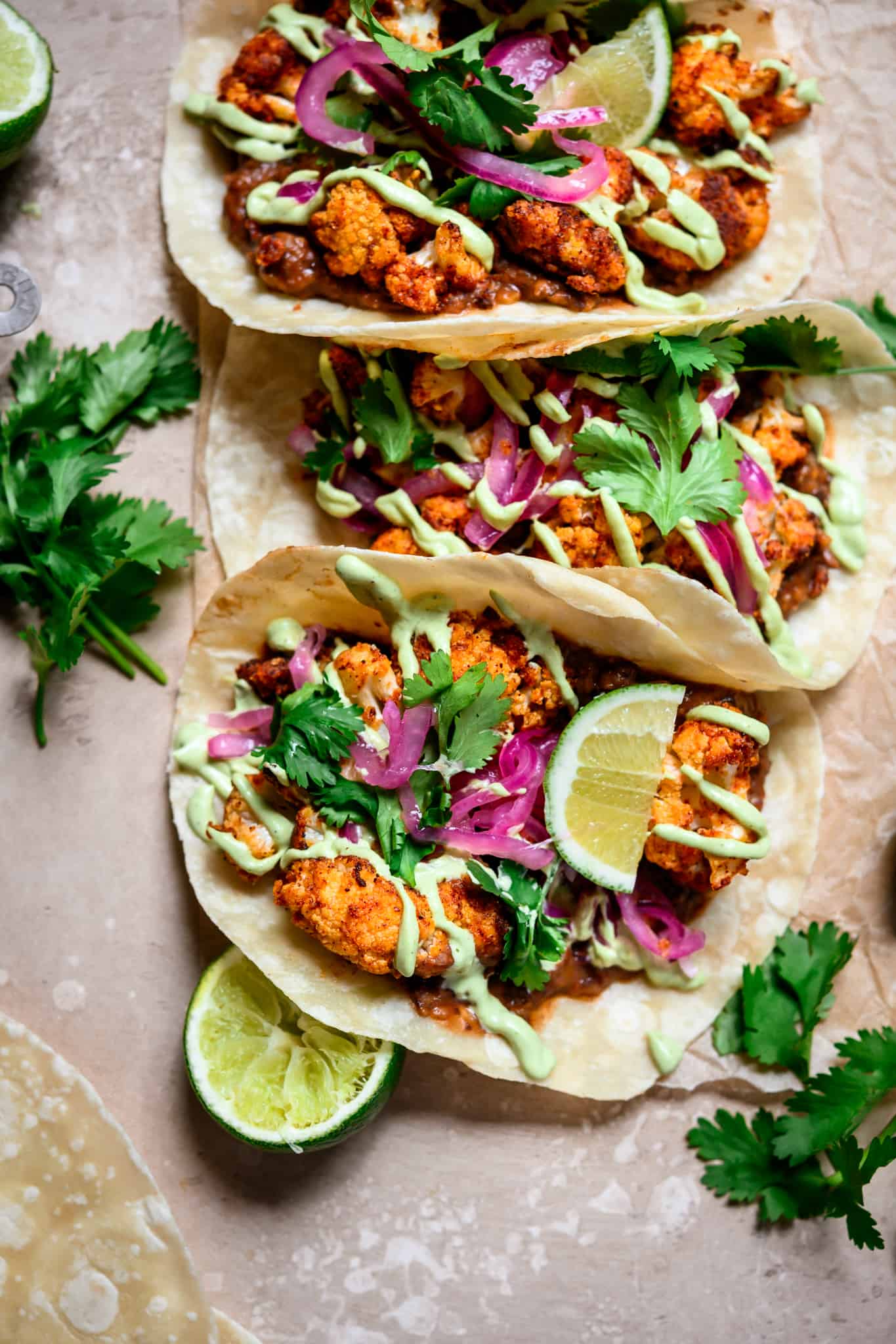 overhead view of tacos with roasted cauliflower, black beans and avocado crema