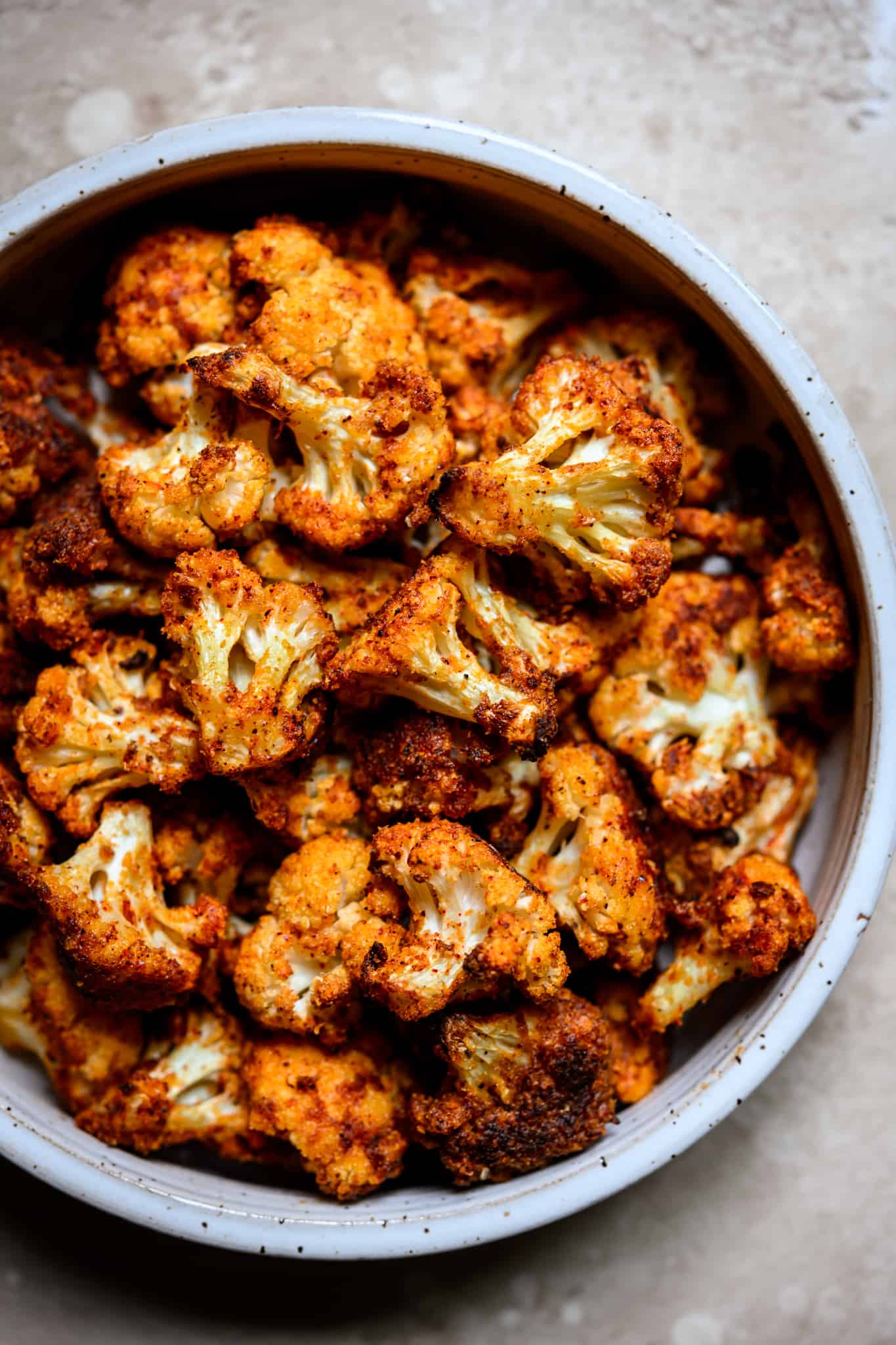 Close up overhead view of crispy spicy cauliflower in a white bowl