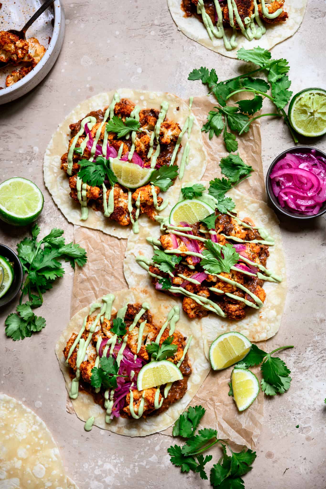 overhead view of tacos with roasted cauliflower, black beans and avocado crema