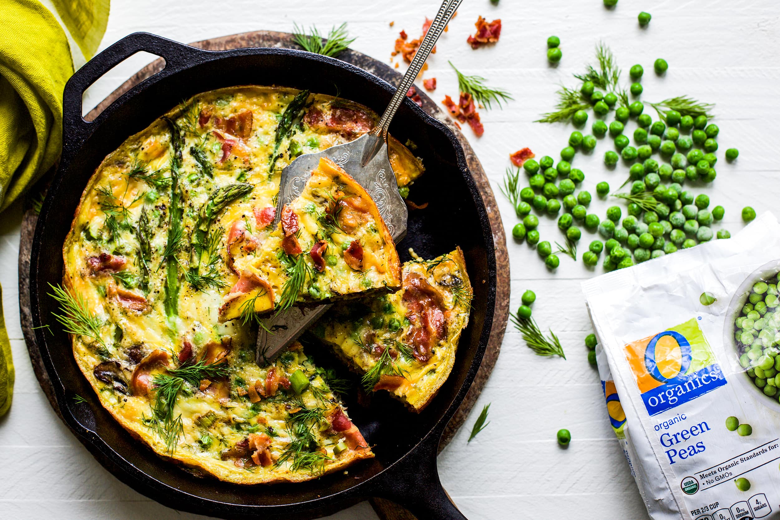 Overhead view of spring frittata in a cast iron skillet on white background