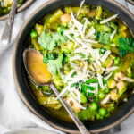Close up overhead of vegetable soup topped with vegan parmesan cheese in a gray bowl