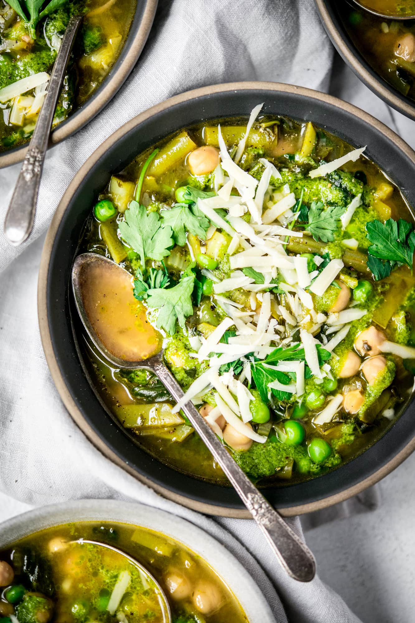 Close up overhead of vegetable soup topped with vegan parmesan cheese in a gray bowl