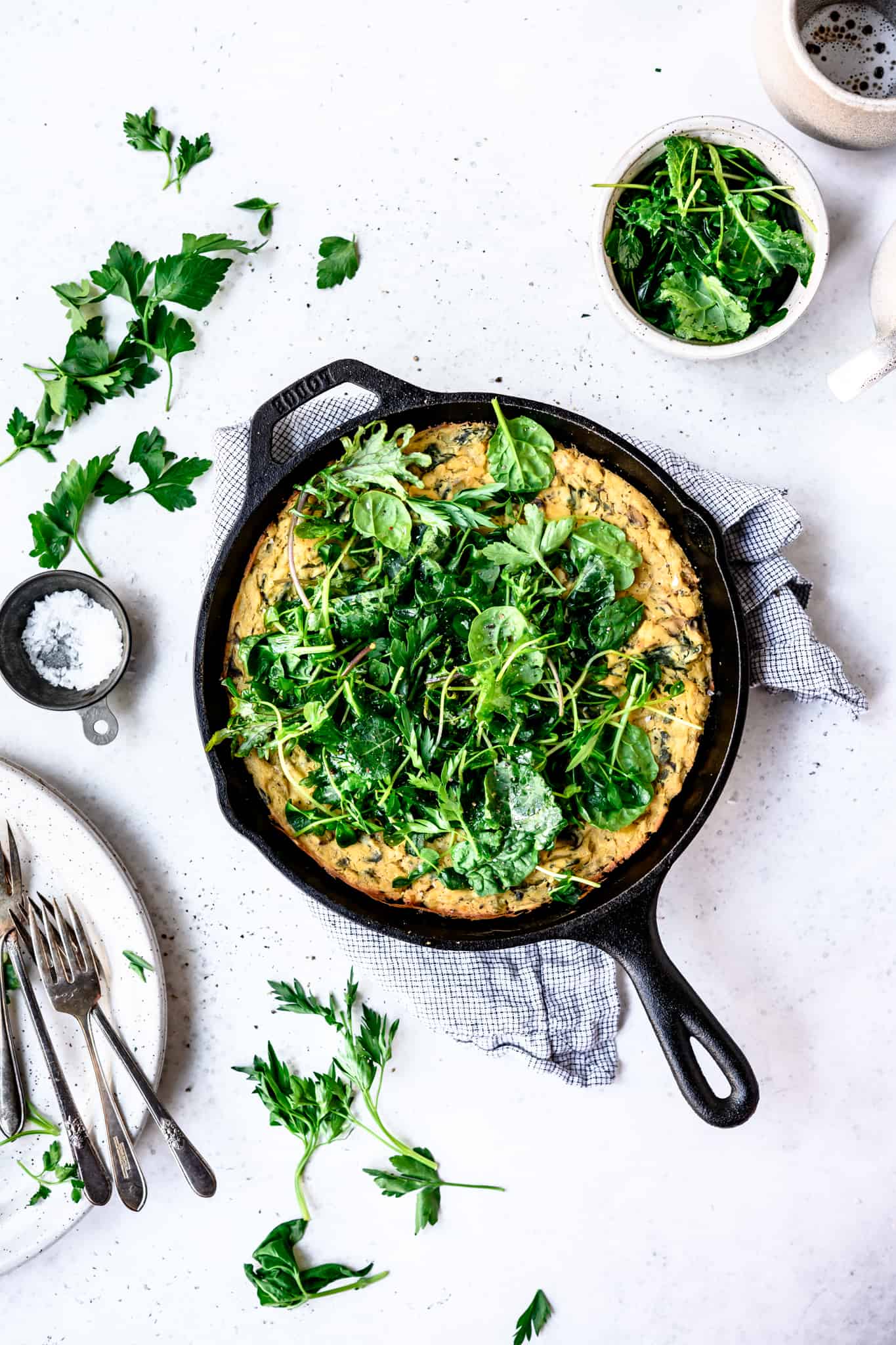 Overhead view of vegan spring vegetable frittata in a cast iron skillet on white background