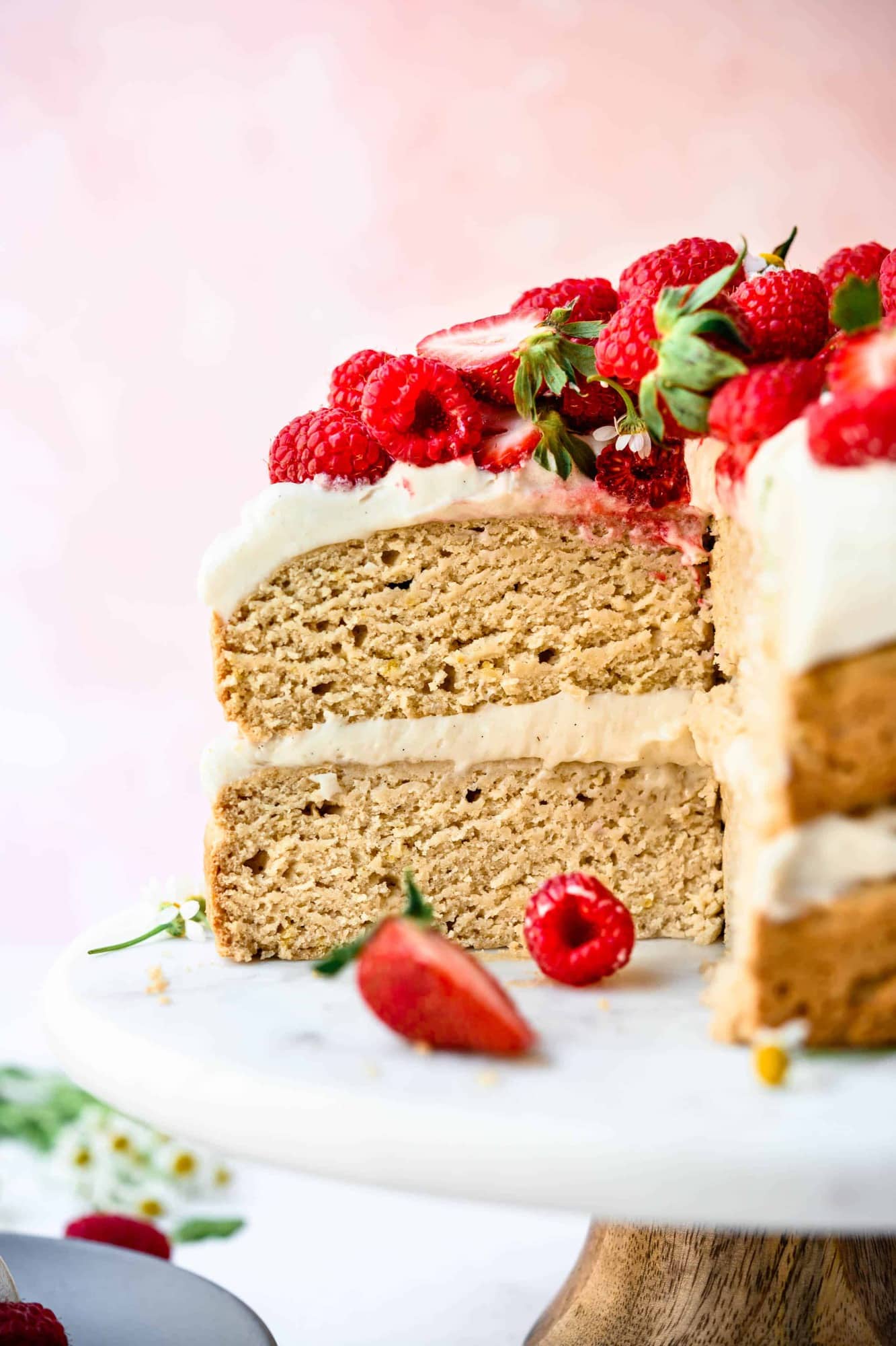 Side view of slice of vegan and gluten free layer cake topped with fresh berries