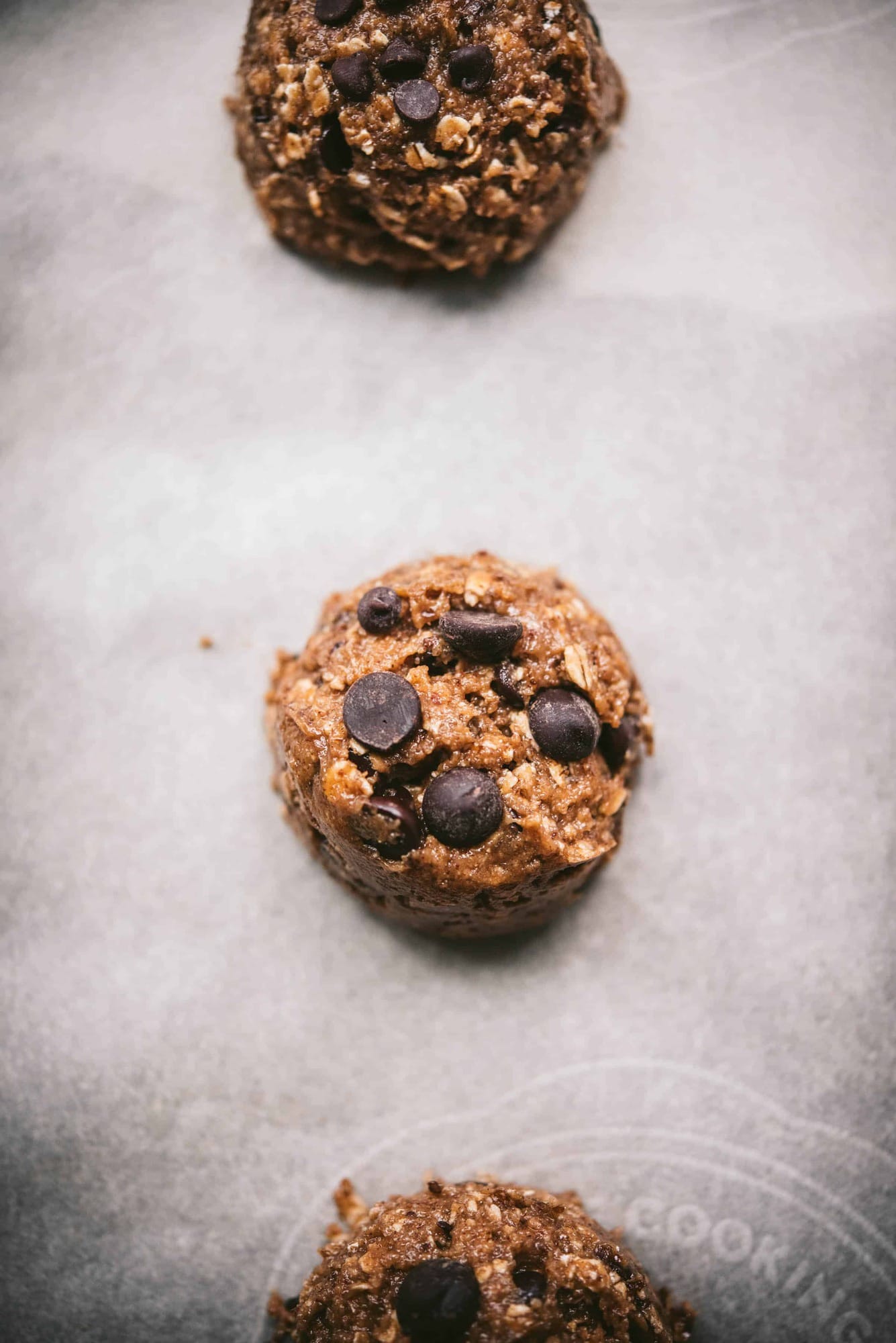 Scoop of chocolate chip oatmeal cookie dough on parchment paper