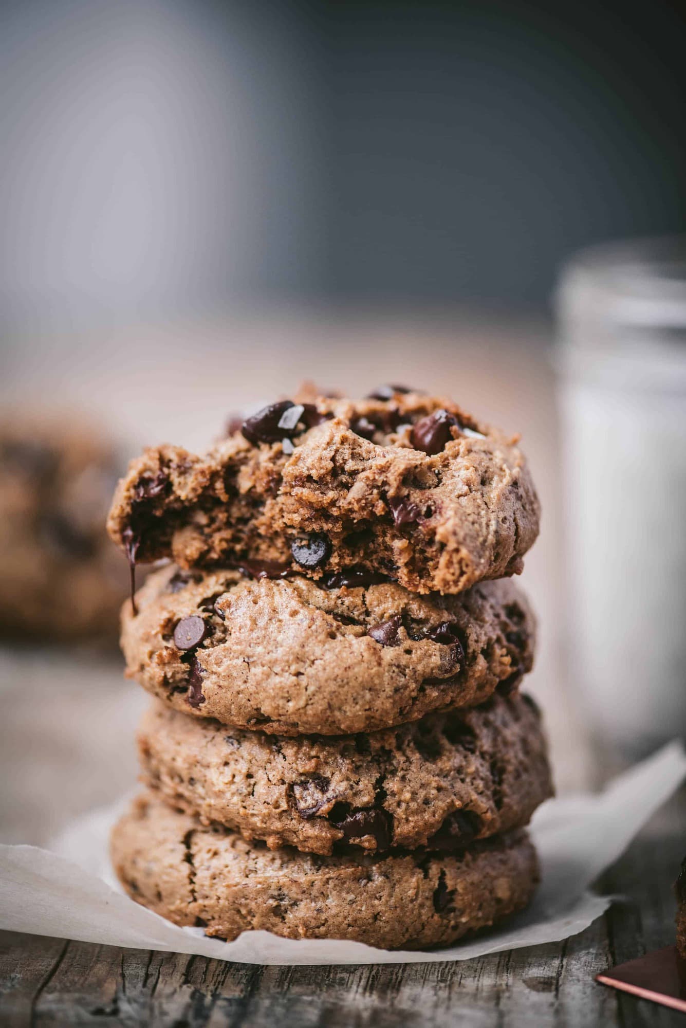 Side view of stack of chocolate chip oatmeal cookies next to jug of milk