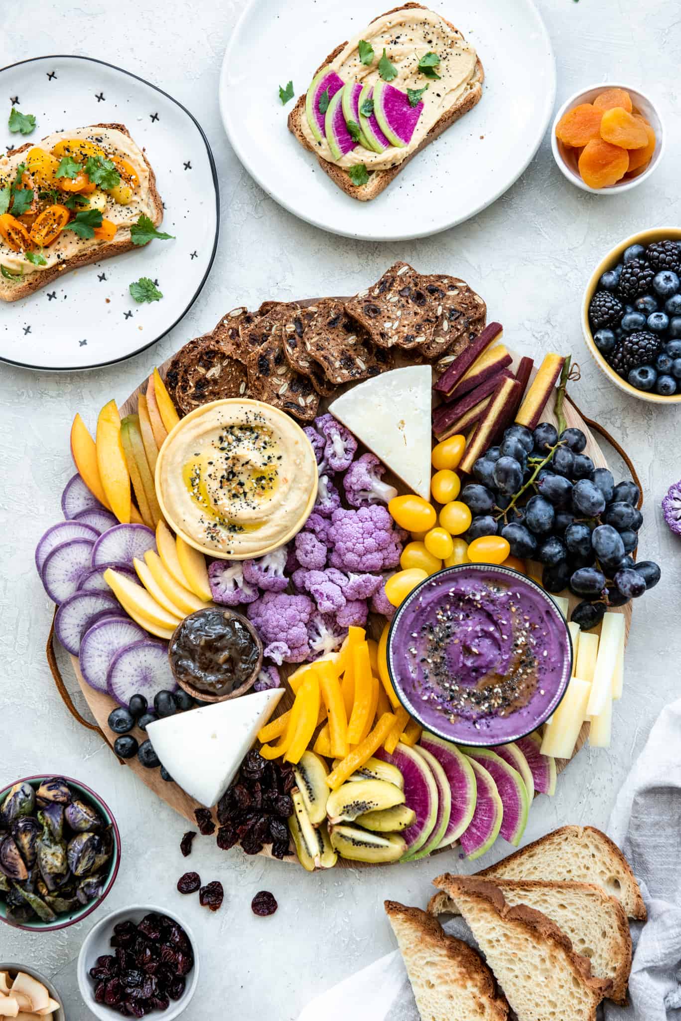 Overhead view of purple and yellow hummus appetizer platter on a gray background