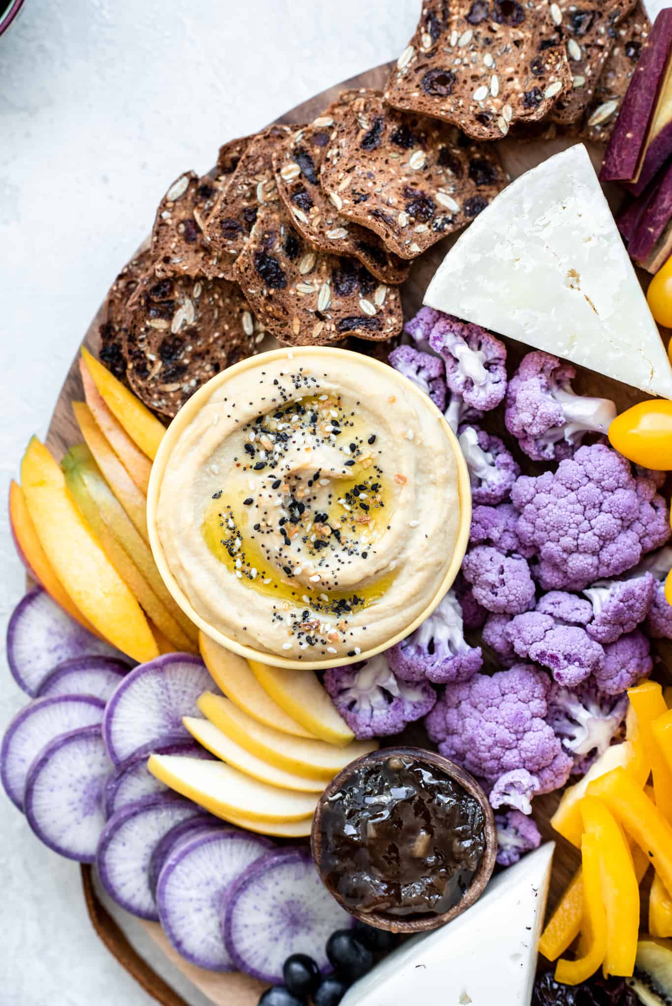 Close up Overhead view of purple and yellow hummus appetizer platter on a gray background
