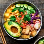 Overhead view of vegan spring roll bowl with crispy tofu and avocado on wood background