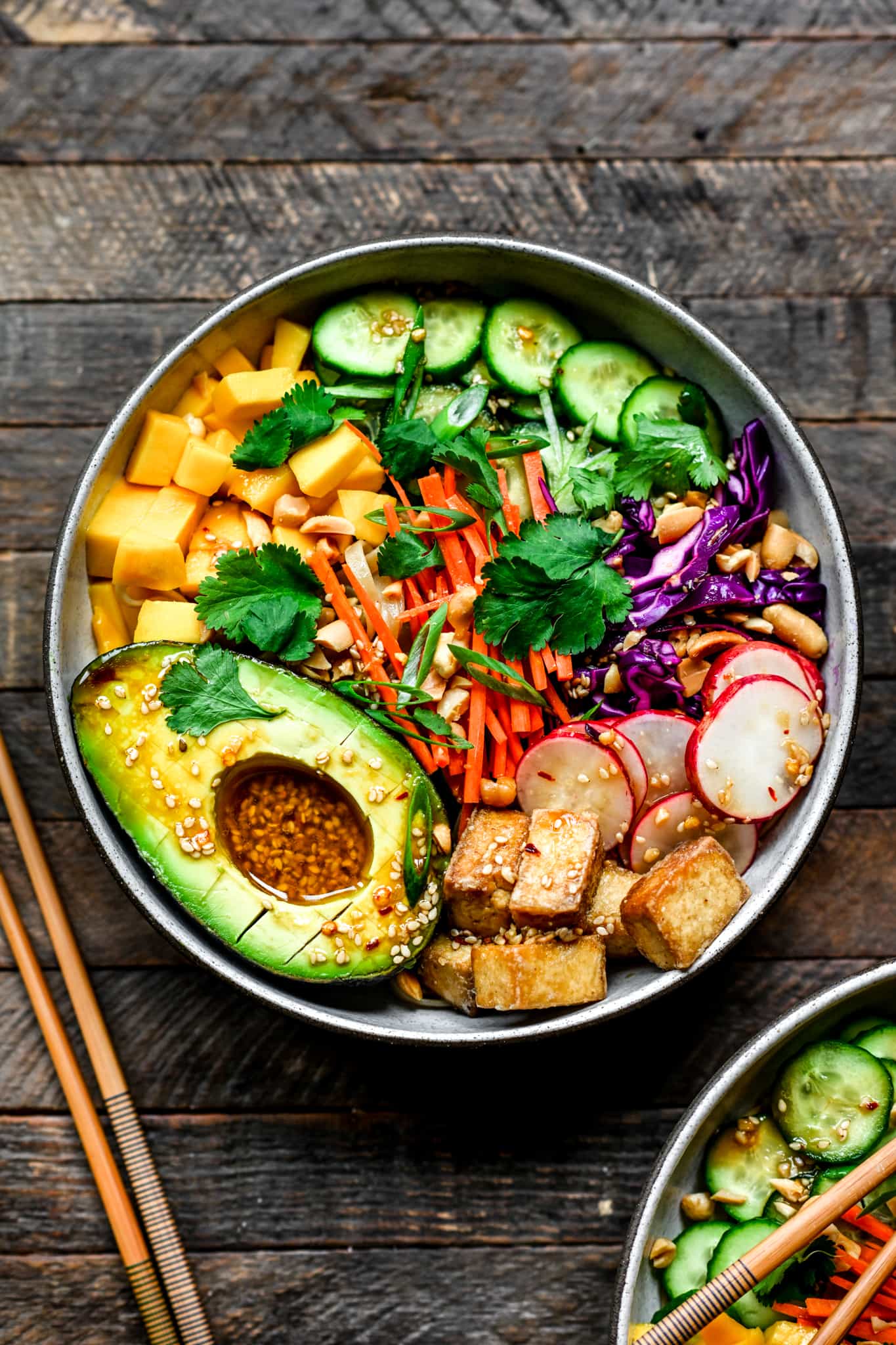 Overhead view of vegan spring roll bowl with crispy tofu and avocado on wood background