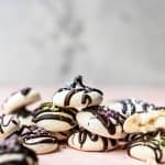 Side view of stack of mini vegan meringues drizzled with dark chocolate