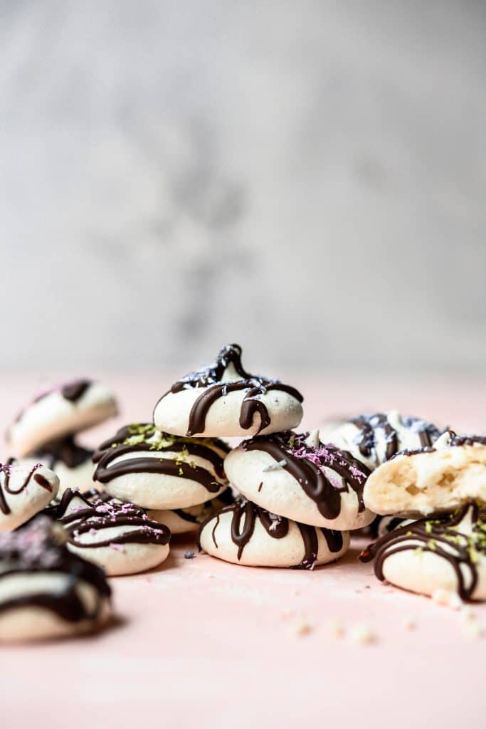 Side view of stack of mini vegan meringues drizzled with dark chocolate