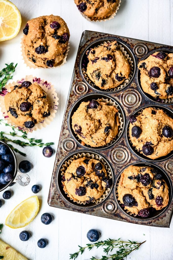 Overhead view of vegan blueberry lemon muffins in rustic muffin tin on white background