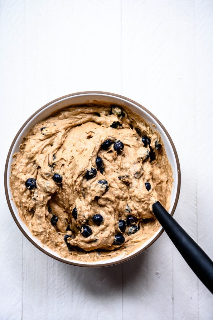 Overhead view of blueberry lemon muffin batter in white bowl on white background