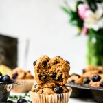 Side view of vegan blueberry lemon muffins stacked on top of each other on white background