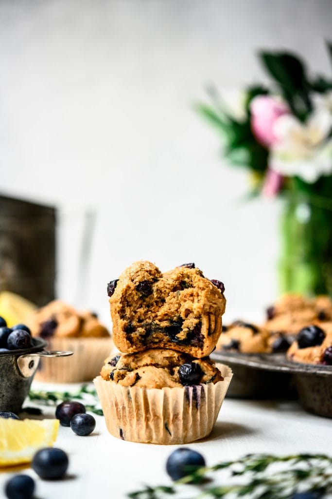 Side view of vegan blueberry lemon muffins stacked on top of each other on white background
