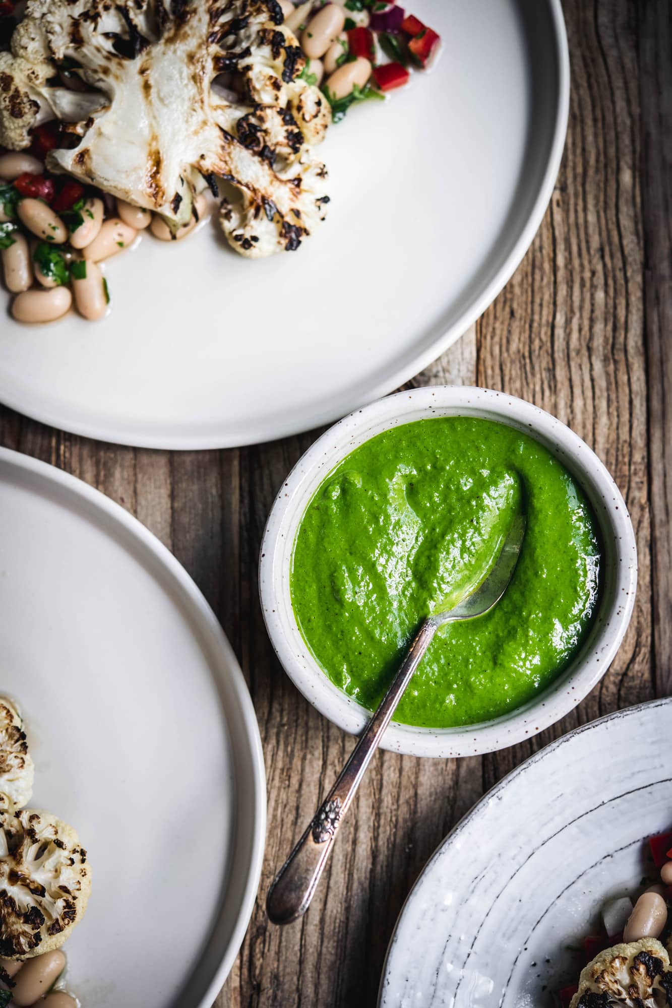 Overhead view of blended chimichurri sauce in a white bowl on wood table