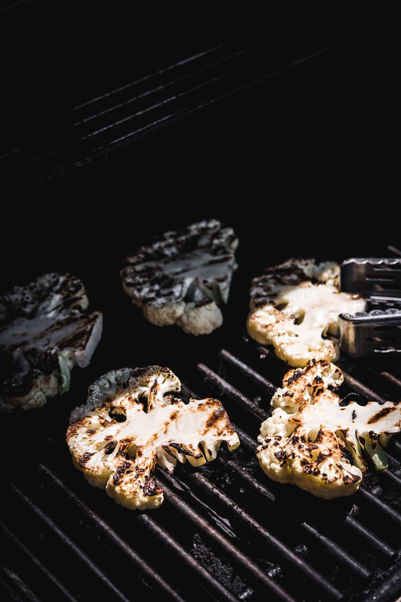 Side view of cauliflower steaks on a grill in sunshine