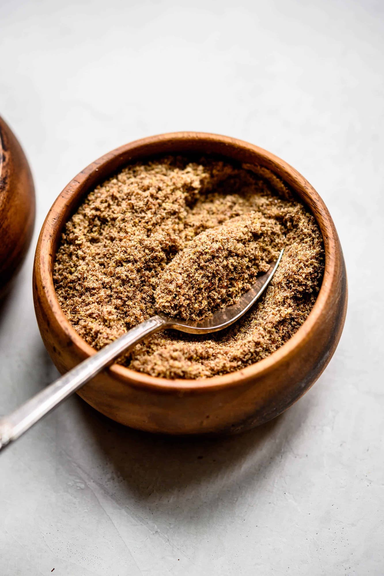 Close up side view of flax meal in a small wooden bowl