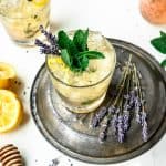 High side view of lemon lavender mint julep garnished with fresh mint, lavender and lemon peel