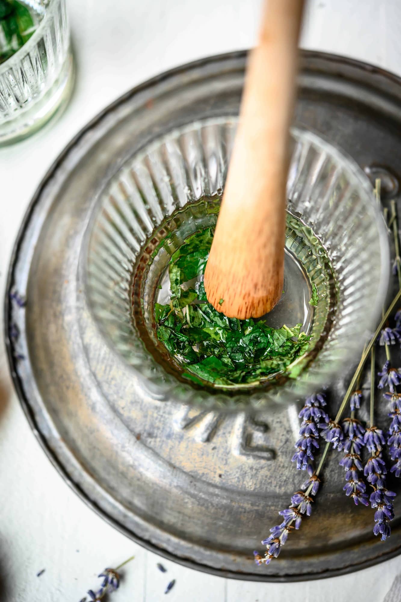 Overhead view of muddling mint in a glass