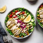 Overhead view of mediterranean salad with falafel and a tahini drizzle on white background