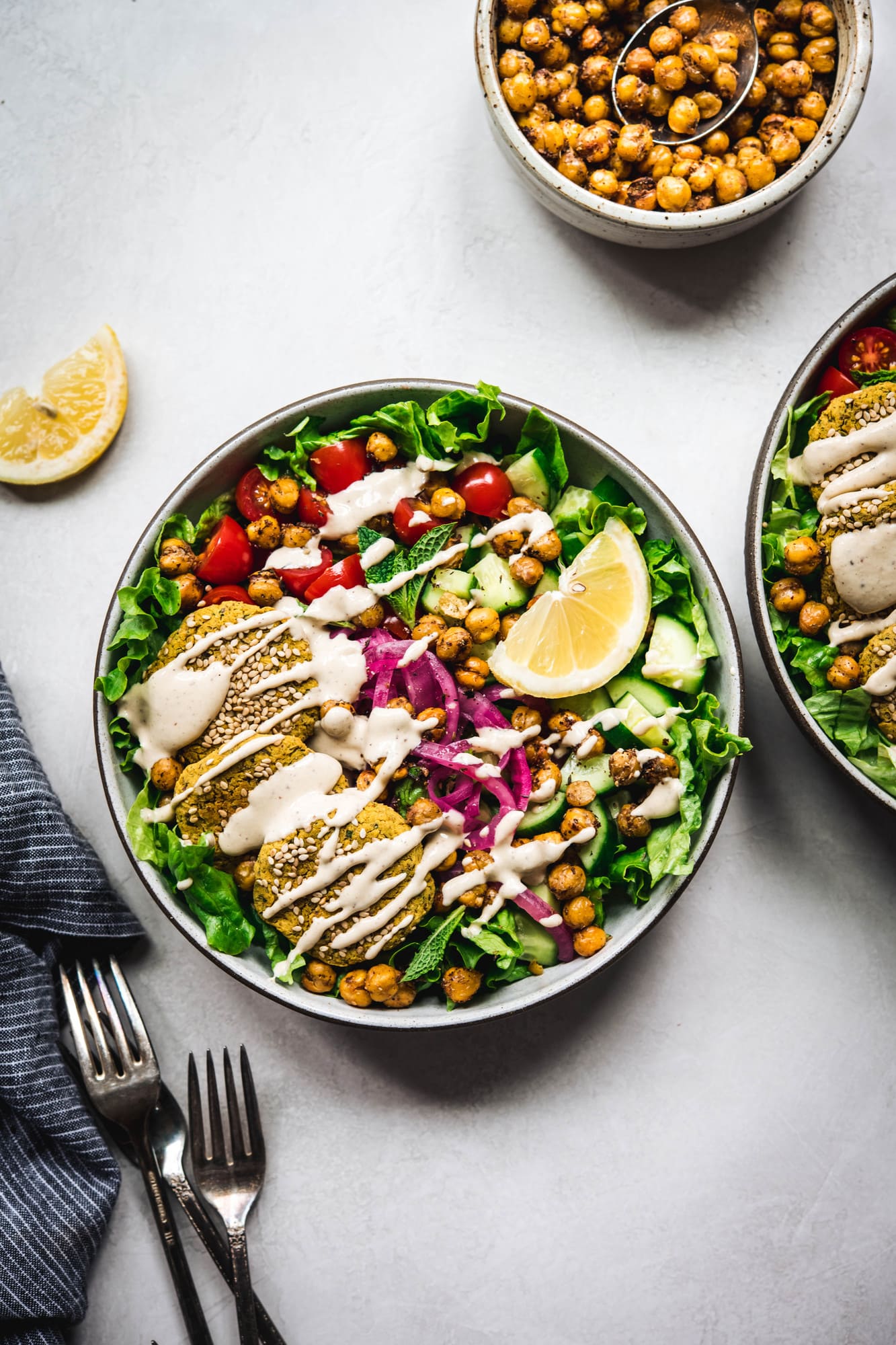 Overhead view of mediterranean salad with falafel and a tahini drizzle on white background