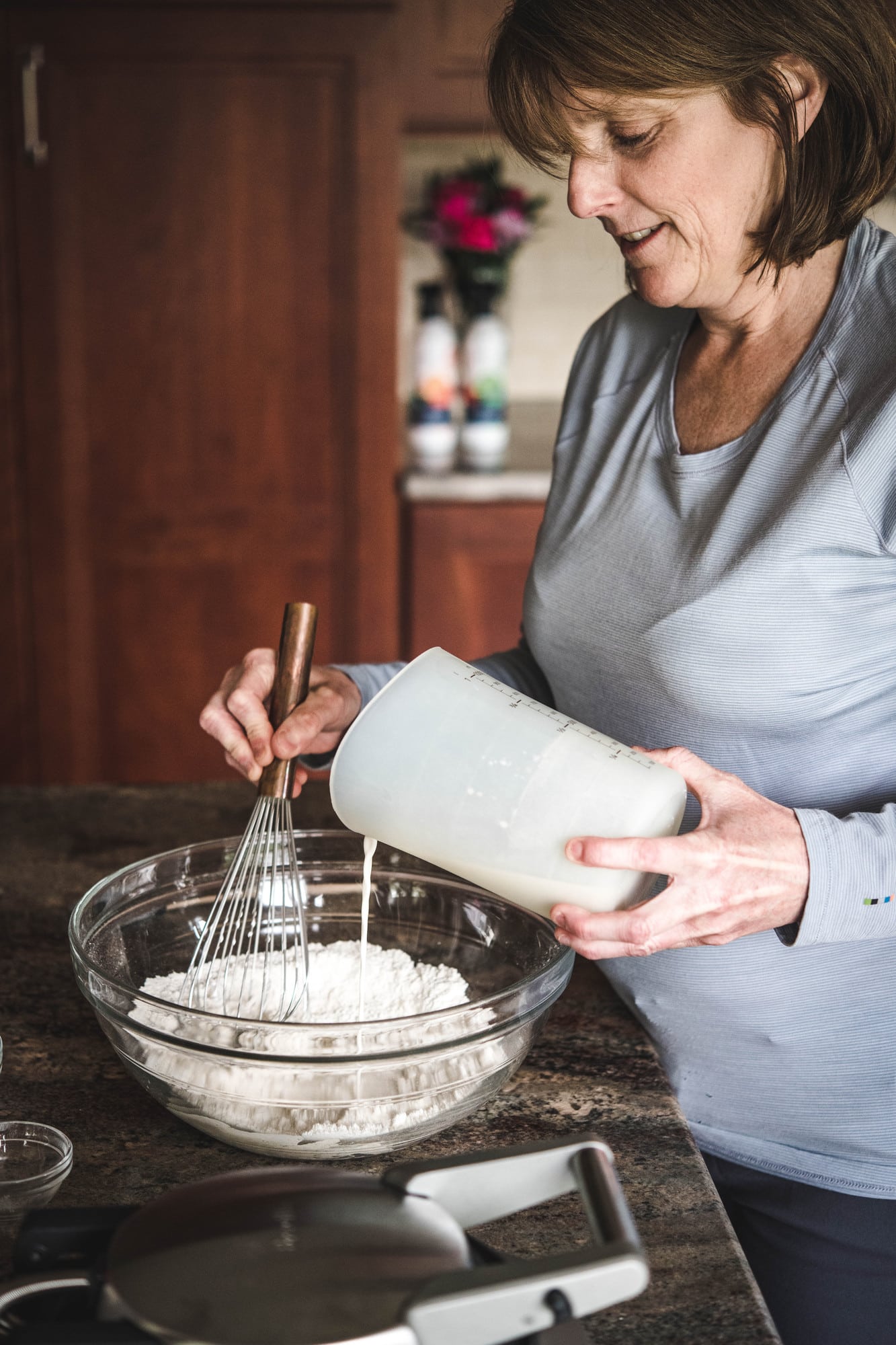 Woman pouring milk into waffle batter