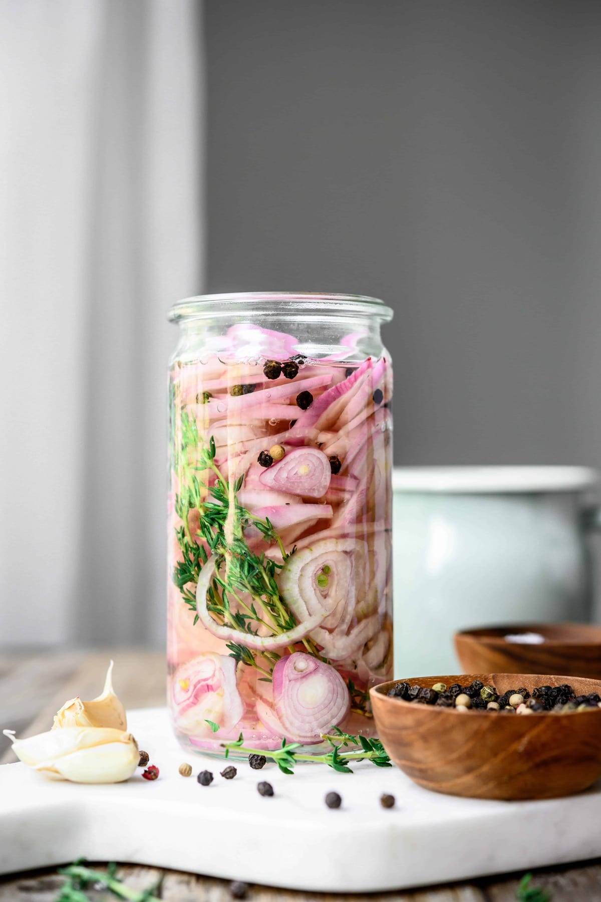 Side view of thyme pickled shallots in glass jar
