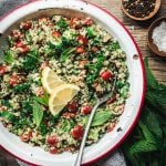 Overhead view of quinoa tabbouleh in a white and red enamel bowl on wood table