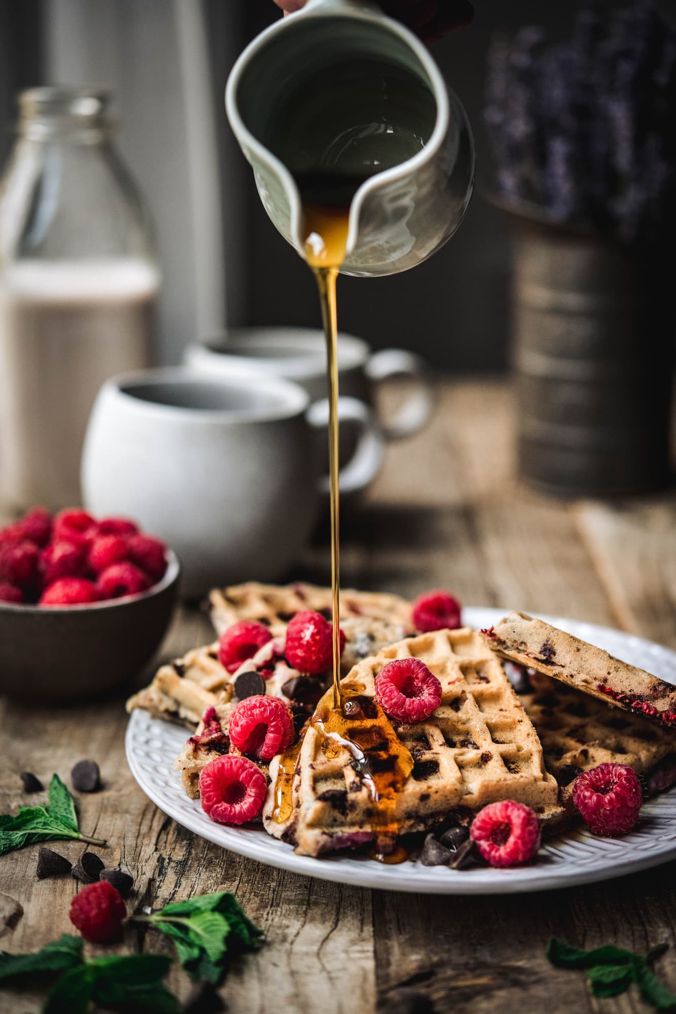 Pouring maple syrup onto raspberry chocolate chip waffles