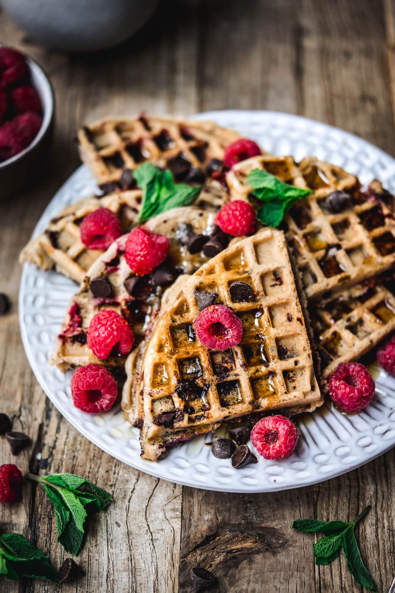 Side view of raspberry chocolate chip waffles on white plate