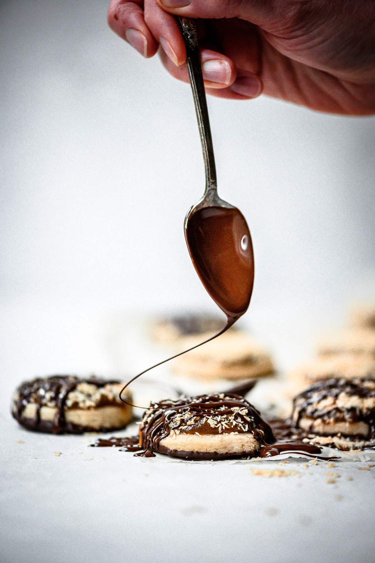 Action shot of drizzling chocolate onto a cookie with a spoon