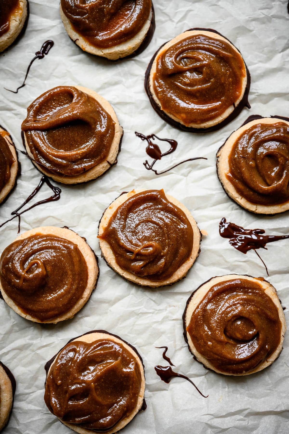 Overhead view of homemade cookies topped with vegan caramel on parchment paper