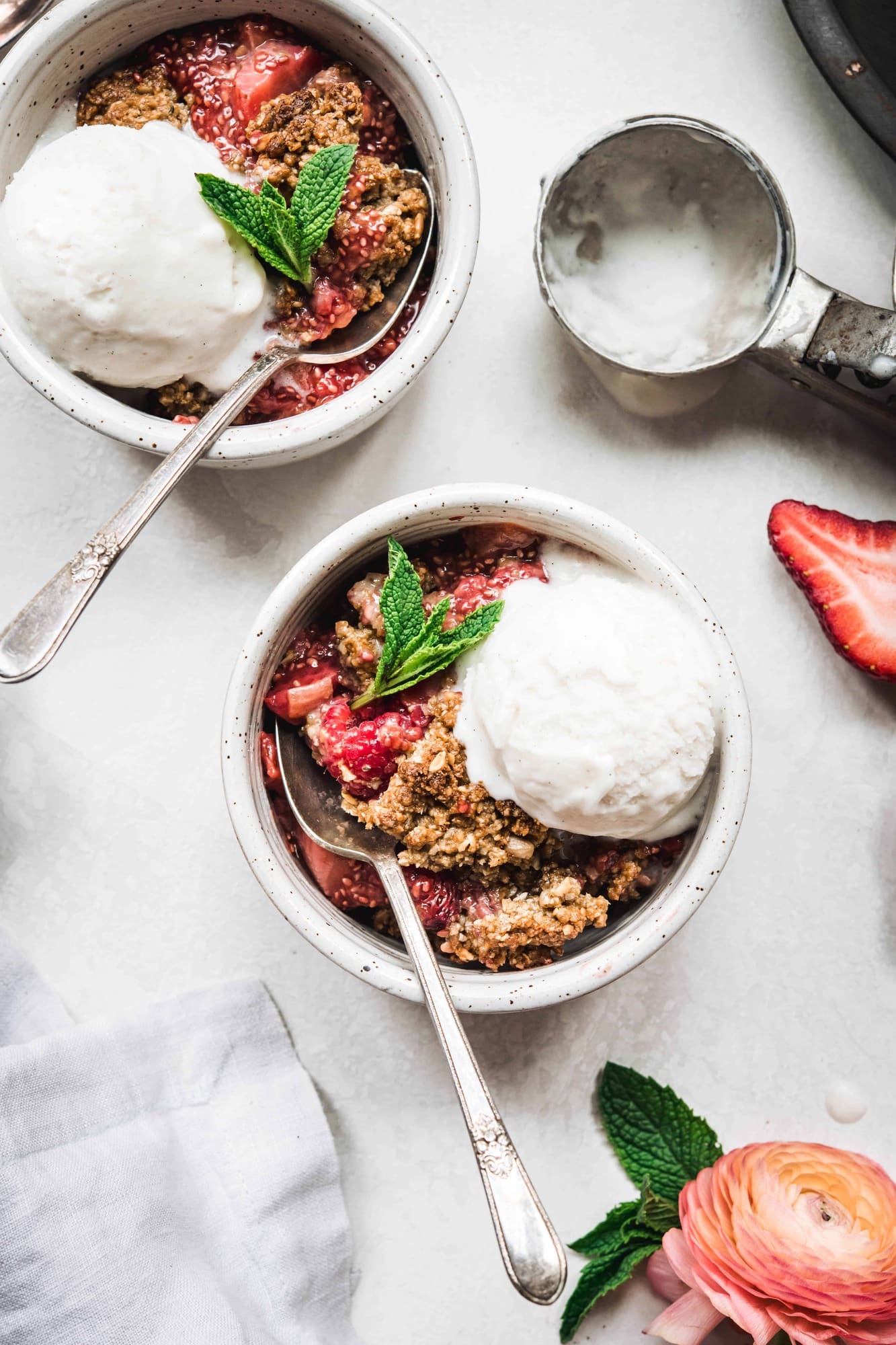 Overhead view of strawberry rhubarb crisp in white bowls with vanilla ice cream