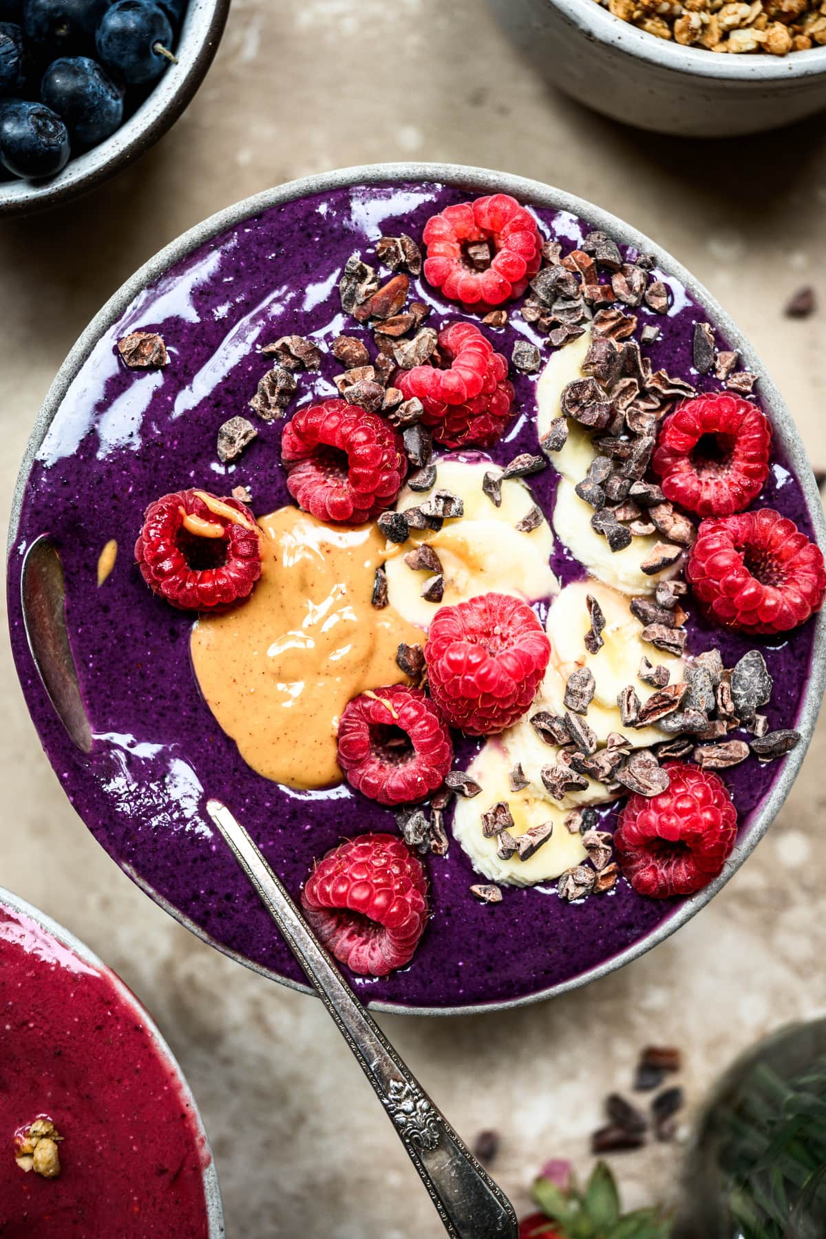 close up view of vegan blueberry pitaya smoothie bowl with peanut butter and berries
