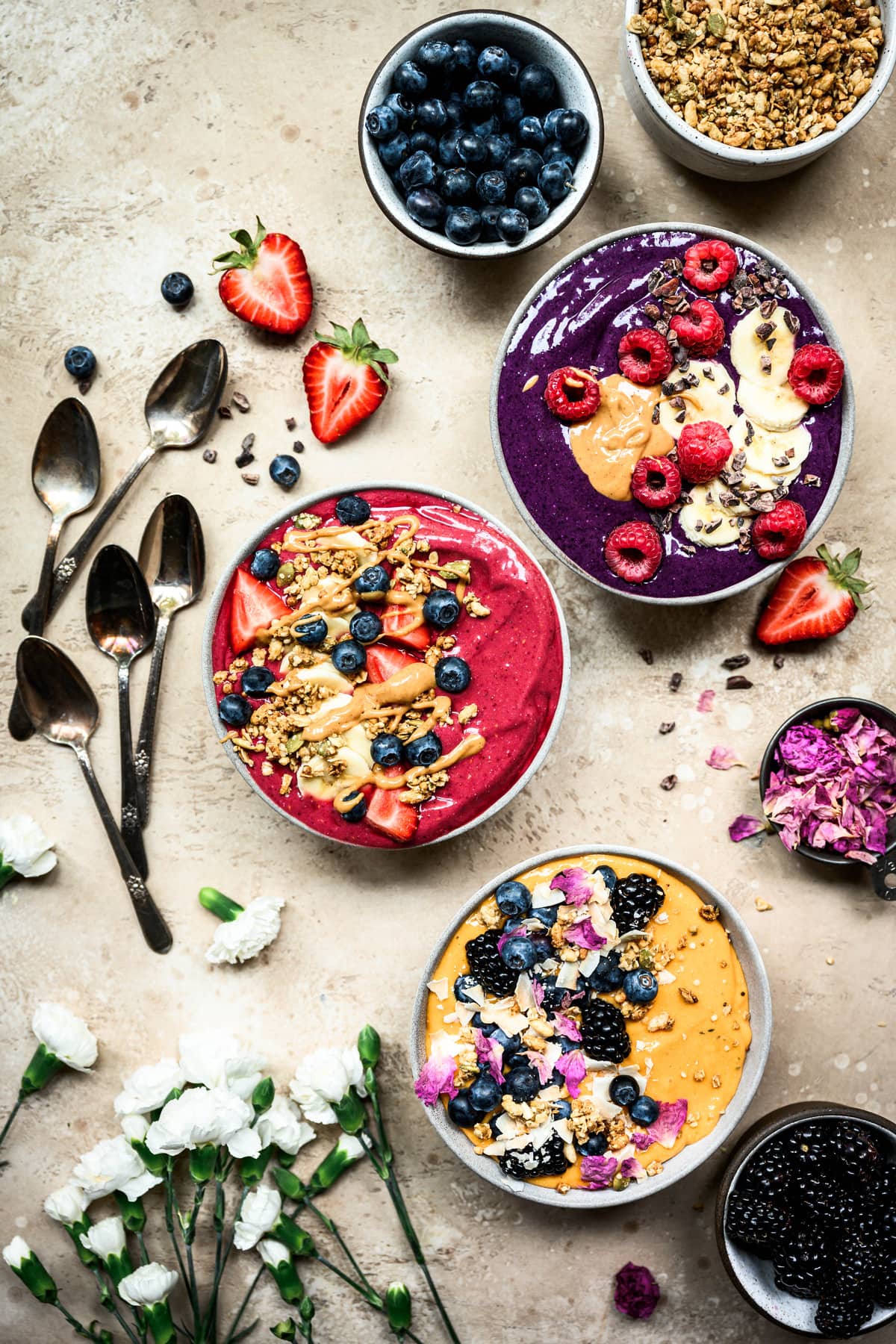 overhead view of three vegan summer smoothie bowls with berries and granola