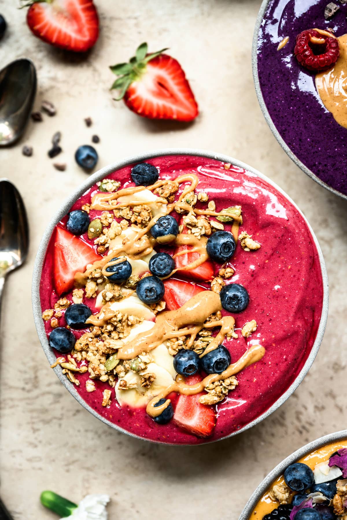 close up view of vegan berry smoothie bowl with peanut butter and granola