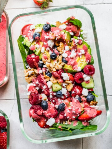 Overhead view of berry avocado salad in a glass container.