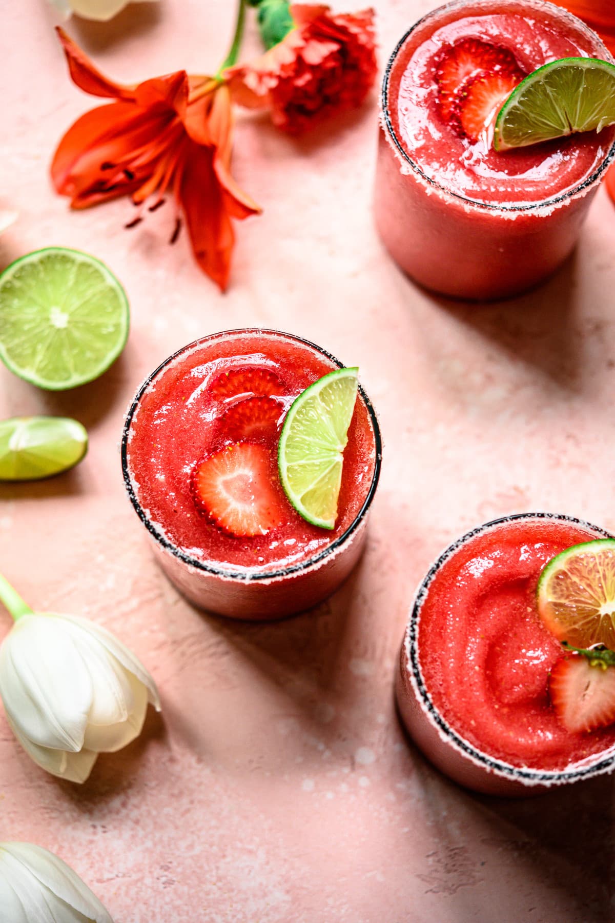 Overhead view of 3 frozen jalapeño watermelon margaritas on pink background