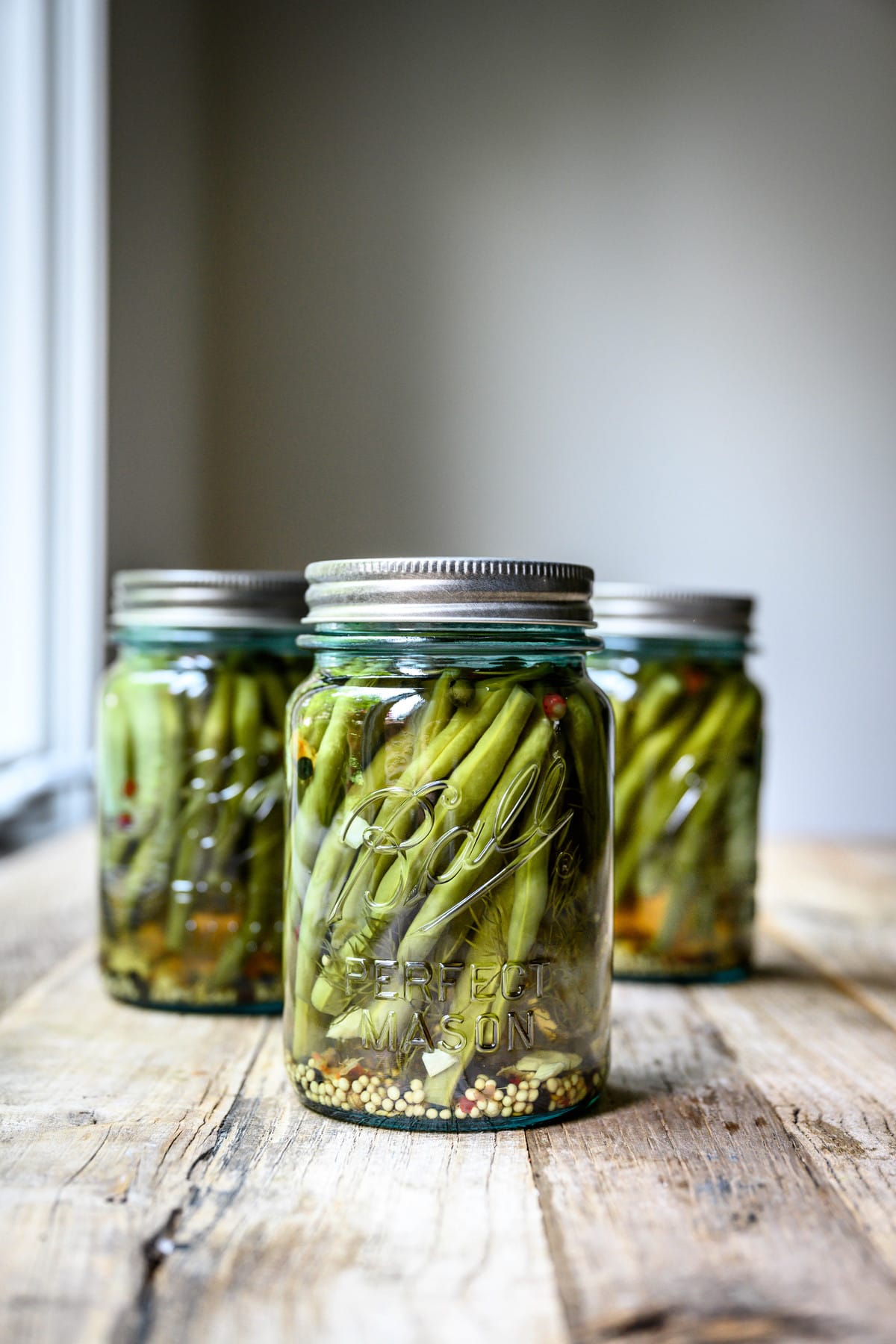 Side view of spicy pickled dilly beans in blue Ball jar