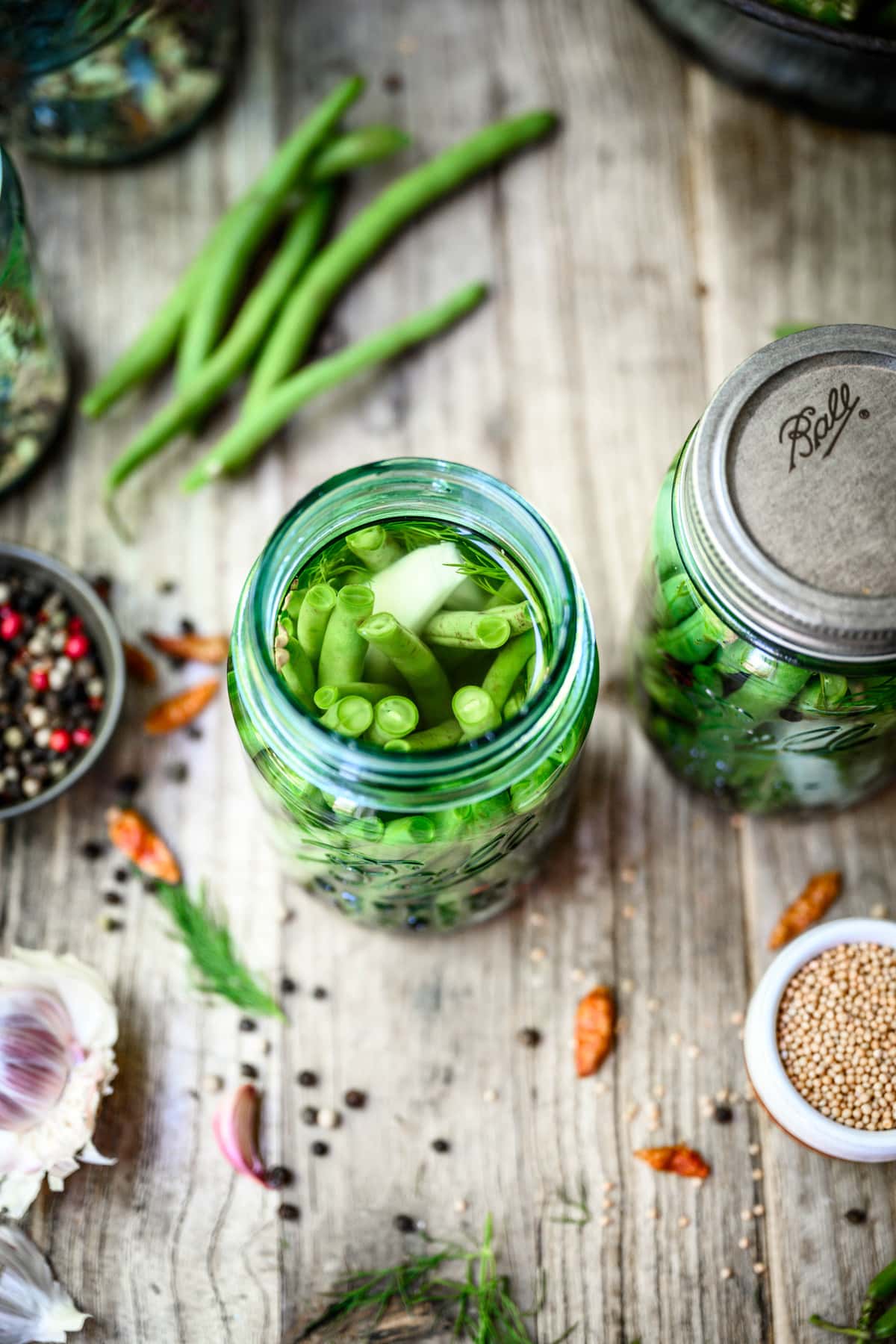 Overhead view of pickled green beans in a canning jar on wood table
