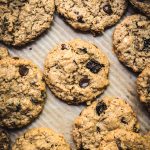 Overhead view of chocolate chip cherry cookies with macadamia nuts on parchment paper-lined tray