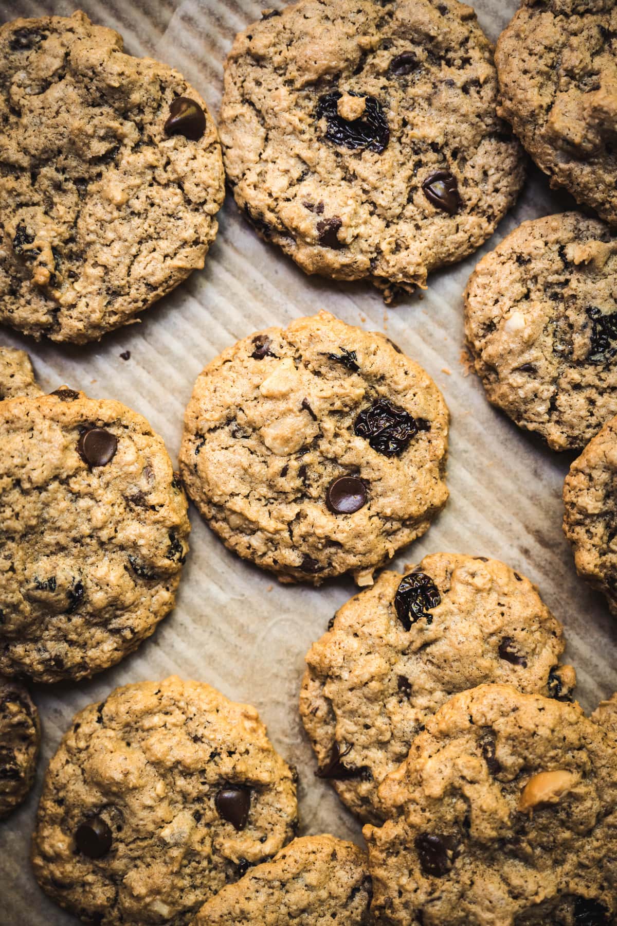 Overhead view of chocolate chip cherry cookies with macadamia nuts on parchment paper-lined tray