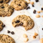 Side view of chocolate chip cherry cookie on parchment paper with bite taken out